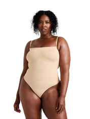 Woman wearing a beige swimsuit against a plain background